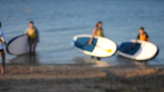 Blurred background. Many people standing on sea and take pictures with sup board