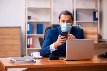 Fototapeta na wymiar Young male employee working in the office wearing mask