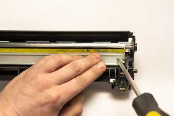 the hand of the master holds the disassembled part of the laser printer cartridge
