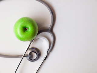 Healthy snack with doctor table. Close up Green apple with Stethoscope for diet an be healthy on white table working and white wooden background. Healthy in Hospital concept.