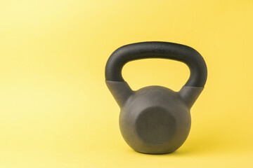Stylish sports kettlebell on a bright yellow background.