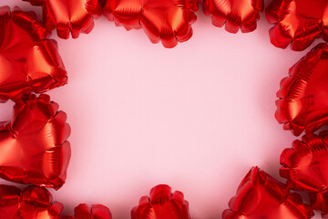 Heart-shaped foil balloons and shiny confetti on a light background. Valentine's day holiday concept. Flat lay.