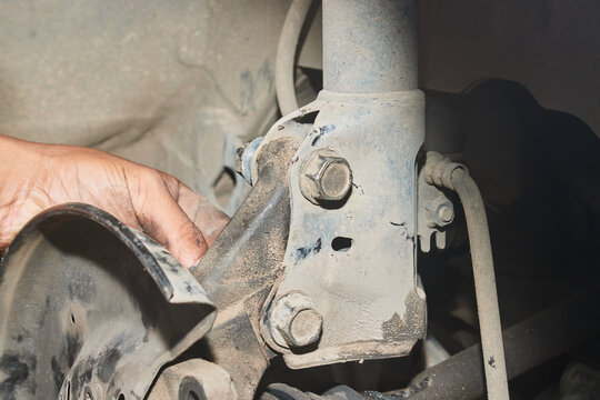 Car Mechanic or Auto Mechanic Loosen Shock Absorber Bolt and Nut from Wheel Hub