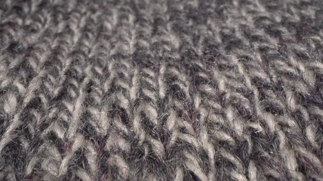 Handcraft knitting grey melange yarn woolen sweater. Cozy sheep wool fabric texture in macro. Soft textile abstract background. Winter fashion clothing industry. Home comfort and cosiness