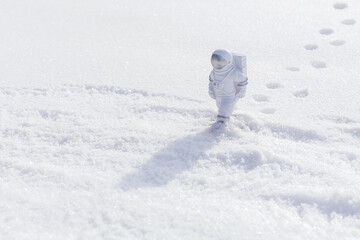 Statuette of an astronaut confidently explores alien planet's surface. Cold planet covered with snow.