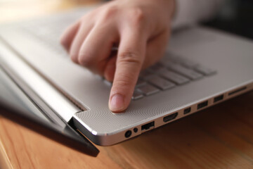 Person hand pushing power button on laptop computer