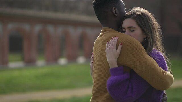Interracial couple empathic embrace. Young woman romantic connection with partner outside