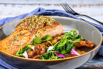 Grilled salmon served with crispy chat potatoes, snow pea tendrils and dukkah butter