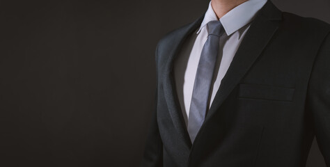 Close up of businessman in black suit and necktie, black background. Copy space for advertising.
