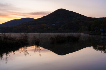 Calming view of Mountain with reflection on the water at the morning sunrise with purple sky in Incheon Grand Park, South Korea