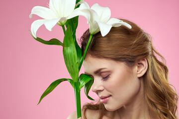 Portrait of a beautiful woman with white flowers in her hands on a pink background Copy Space cropped view