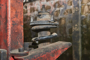 Side View Shock Absorber in Spring Compressor on Concrete Background