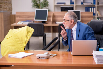 Aged businessman employee looking after newborn at workplace