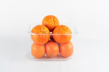 Fresh tangerines in a glass jar on a white background