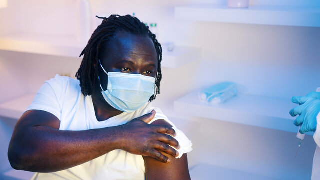 Vaccination and immunization with mRNA vaccine against coronavirus. Young african american black man with face mask getting vaccinated. High quality photo