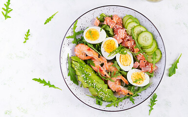 Ketogenic diet breakfast. Salt salmon salad with boiled shrimps, prawns, cucumbers, arugula, eggs and avocado. Keto, paleo lunch. Top view, overhead