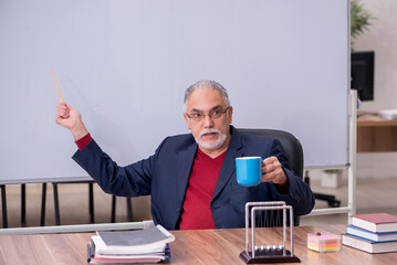 Old teacher physicist sitting in the classroom