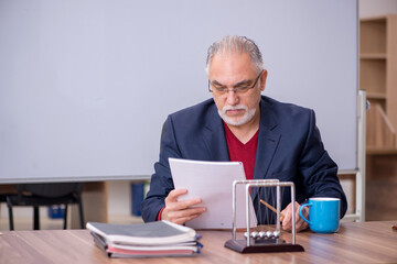 Old teacher physicist sitting in the classroom