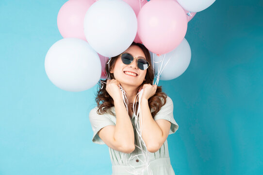 Young Asian girl holding balloons with happy expression on background