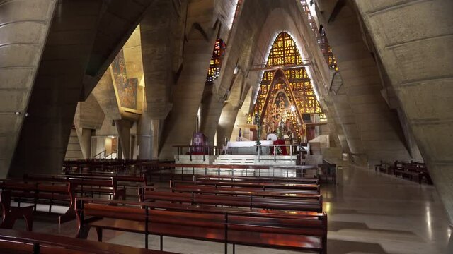 The interior of an old Christian church in the Dominican Republic. Altar and wooden benches for parishioners. Solemn atmosphere of the temple. Antique stained glass windows. Faith and repentance.