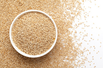 Close-up of Organic White Sesame seeds (Sesamum indicum) or white Til with shell in white ceramic bowl with the gradient background of White Sesame seeds. Top view 