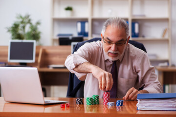 Old male employee in gambling concept at workplace