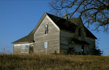 Better Days. An abandoned house on a hill, side lit by the early morning light with a broken window. Near Pure Air, Missouri USA 2007