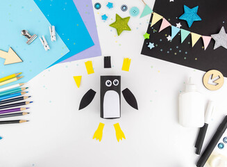 Step-by-step instructions for making a penguin with children from a toilet roll of paper and colored paper. Step 3