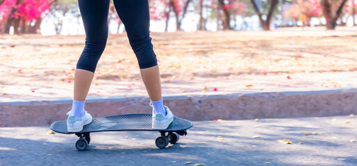 Close-up Asian women surf skate or skateboard outdoors on beautiful morning. Happy young women play surf skate at ramp park on morning time. Close up Asian women leg wear sneaker play surf skate 