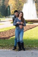 Happy Young Couple Standing Outdoors and Using Smartphone