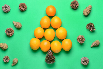 Christmas tree made of oranges and pine cones on color background