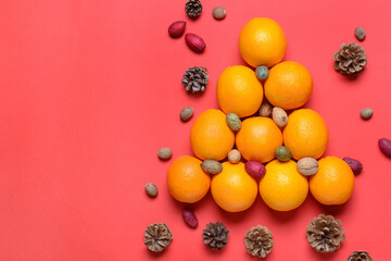 Christmas tree made of oranges, walnuts and pine cones on color background