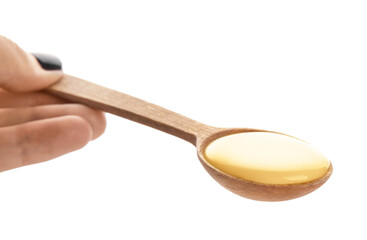 Hand with spoon of sweet condensed milk on white background