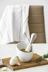 Mortar with spices and pestle on light table