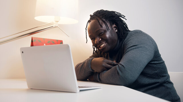 Young african american black man having a video call using laptop. Showing gift to his girlfriend. High quality photo