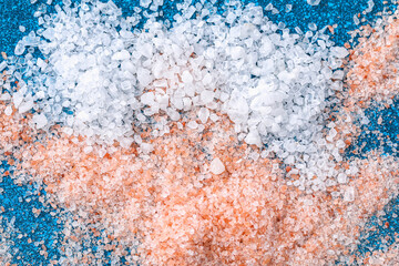 Pink coarse salt crystals on a blue table. Himalaya salt. Background for advertising salty.