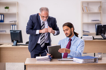 Old male boss and young employee working in the office