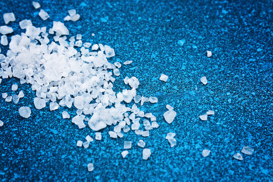 Coarse salt crystals on a blue table. sea salt. Background for advertising salty.