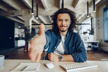 Attractive young handsome businessman sitting in office and talking to you