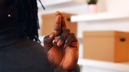 close up fingers crossed, African american black man holding crossed fingers in the new apartment....
