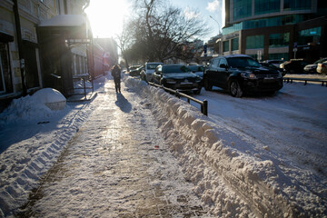 Fototapeta premium Large snowdrift after cleaning the sidewalk, road in the city.
