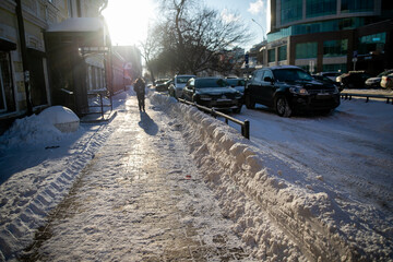 Large snowdrift after cleaning the sidewalk, road in the city.