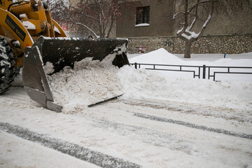 Snow removal in the city with a tractor or an excavator. Dirty snow.