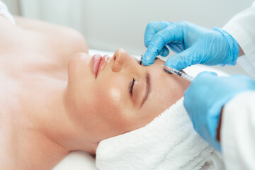 Naklejka premium Portrait of a beautiful woman having an injection of botox in her face
