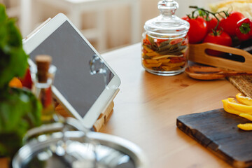 Naklejka na ściany i meble Kitchen table with food and digital tablet on it close up