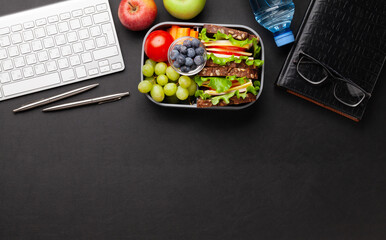 Healthy office lunch box with sandwich and fresh vegetables
