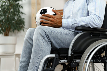 Invalid or disabled man sitting on wheelchair and holding soccer ball