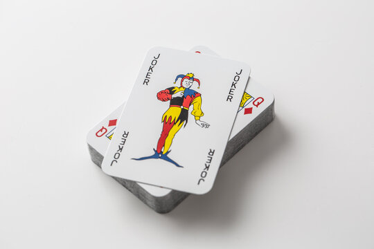 Joker card on top of pile of playing cards on an isolated white background