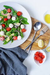 italian cuisine - healthy tasty salad with cherry tomatoes, avocado, spinach leaves, Mozzarella and red onion with olive oil dressing