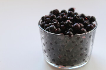 eating blueberry or currant berries in a glass glass on a white light background with a place to text the view from the side